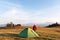 Tourist in red jacket near his tent in mountains camp