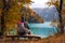 Tourist is resting on the bench near beautiful mountains lake with turquoise water and colorful forest. Tourism, trekking, hiking