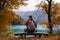Tourist is resting on the bench near beautiful mountains lake with turquoise water and colorful forest. Tourism, trekking, hiking
