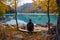 Tourist is resting on the bench near beautiful mountains lake with turquoise water and colorful forest. Tourism, trekking, hiking