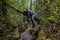 Tourist resting like a feline on a fallen tree on a trail in the mountains of chilean patagonia