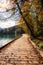 Tourist route on the wooden floor along the famous alpine Bled lake Blejsko jezero in Slovenia, amazing autumn landscape
