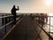 Tourist sit on mole handrail and takes pictures.Wooden boardwalk