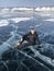 Tourist sitting on the surface of the cracks of the frozen Lake Baikal in the winter season in Siberia, Russia. Lake Baikal is the