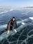 Tourist sitting on the surface of the cracks of the frozen Lake Baikal in the winter season in Siberia, Russia. Lake Baikal is the