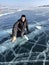 Tourist sitting on the surface of the cracks of the frozen Lake Baikal in the winter season in Siberia, Russia. Lake Baikal is the