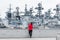 Tourist from South Korea admires view on seaport with warships of Russian Pacific Fleet in city downtown. Warships Varyag, Gromkiy