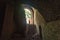 tourist standing in arch of weathered dark corridor of old fortress