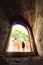 tourist standing in arch of weathered dark corridor of old fortress