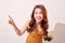 Tourist standing isolated on beige background and joyfully pointing to the sky. Lady using camera while travel. Independent travel