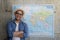 Tourist standing with worldmap on wall, plans for next destination, lifestyle concept.