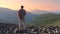 A tourist stands and looks at the panorama of mountains at sunset. A man with a backpack is Hiking in the mountains