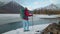 Tourist stands near the lake in mountais in winter