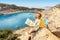 Tourist student with map and greek flag standing on top of the hill at background of the inspirational blue lagoon bay. Solo