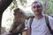 A tourist takes a selfie photo with a barbary macaque living in forest near the Ouzoud Falls.