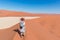 Tourist taking photo at Sossusvlei, Namibia. Scenic sand dunes, Namib desert, Namib Naukluft National Park, travel adventure in Af