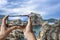 Tourist taking photo of stunning view of Dubrovnik city wall. Man holding phone and taking picture of fortress walls, rocky coast