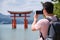 Tourist taking photos of Itsukushima Jinja Otorii on the sea of Miyajima, Japan.