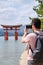 Tourist taking photos of Itsukushima Jinja Otorii on the sea of Miyajima, Japan.