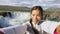 Tourist taking video selfie on travel by Godafoss waterfall on Iceland