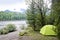 Tourist tent among bushes and trees on the banks of a mountain river.