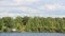 Tourist tent on the forest shore of a lake or river. A man is standing next to the tent