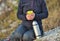 Tourist with a thermos. woman pours tea on the nature