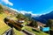 A tourist train traveling on the railway thru Wengen village by green grassy hillside with Jungfrau mountain