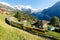 A tourist train travels on the railway thru Wengen village on a green grassy hillside with Jungfrau Mountain & Lauterbrunnen Valle