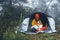 Tourist traveler in camp tent hugging red shiba inu on background froggy forest, hiker person with puppy dog in mist nature trip