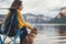 Tourist traveler girl relax together dog on foggy mountain scape,  woman hug pet rest on lake shore nature trip