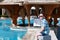 Tourist and traveler is sitting on his traveled suitcase on swimming pool of hotel resort, enjoys view on environment and resting.