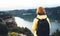 Tourist traveler with yellow backpack standing on green top on mountain, hiker view from back looking on hills and mountain river