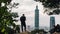 Tourist trekker taking a photo of Taipei 101 Skyscraper from Xiangshan Elephant Mountain in the evening in Taipei, Taiwan