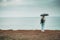 A tourist with an umbrella in the rain stands on a cliff and looks at the ocean from the back. tourist place.