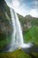 Tourist under the waterfall in Iceland, Adventure photo, edit sp