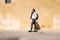 Tourist walking by the ancient medieval Mdina streets with a city backpack and enjoying a historical place. Smiling Female