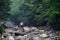 Tourist walks along the stones along the mountain river