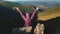 Tourist waving hands sitting on mountain top peak