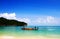 Tourist wearing orange life jacket and sitting in long tail boat for take trip on the sea with mountain and clear blue sky for bac