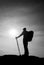 Tourist in windcheater with sporty trecking poles in hands stand on rocky view point.