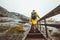 Tourist woman with backpack climbing up stairs in rocky mountains