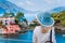 Tourist woman in blue sunhat on view point platform admire view of colorful tranquil village Assos on sunny day