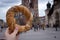 Tourist woman eating bagel obwarzanek traditional polish cuisine snack waling on Market square St. Mary& x27;s Basilica