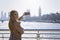 A tourist woman in a elegant coat takes pictures of the Big Ben clocktower in London