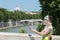 Tourist woman in flower sundress with tablet in hands standing at Rome bridges and masterpiece dome background