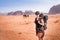 Tourist woman with friends in a desert. Jordan natural park Wadi Rum. Backpacker on the road. Woman hiker with backpack