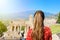 Tourist woman in Italy. Back view of girl visiting Greek theather of Taormina with Etna volcano on the background, Sicily