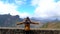 A tourist woman looking at Roque Nublo from a viewpoint with her arms open