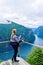 Tourist woman looks at Geirangerfjord and Seven Sisters Waterfall near small village of Geiranger. View from Eagles Road viewpoint